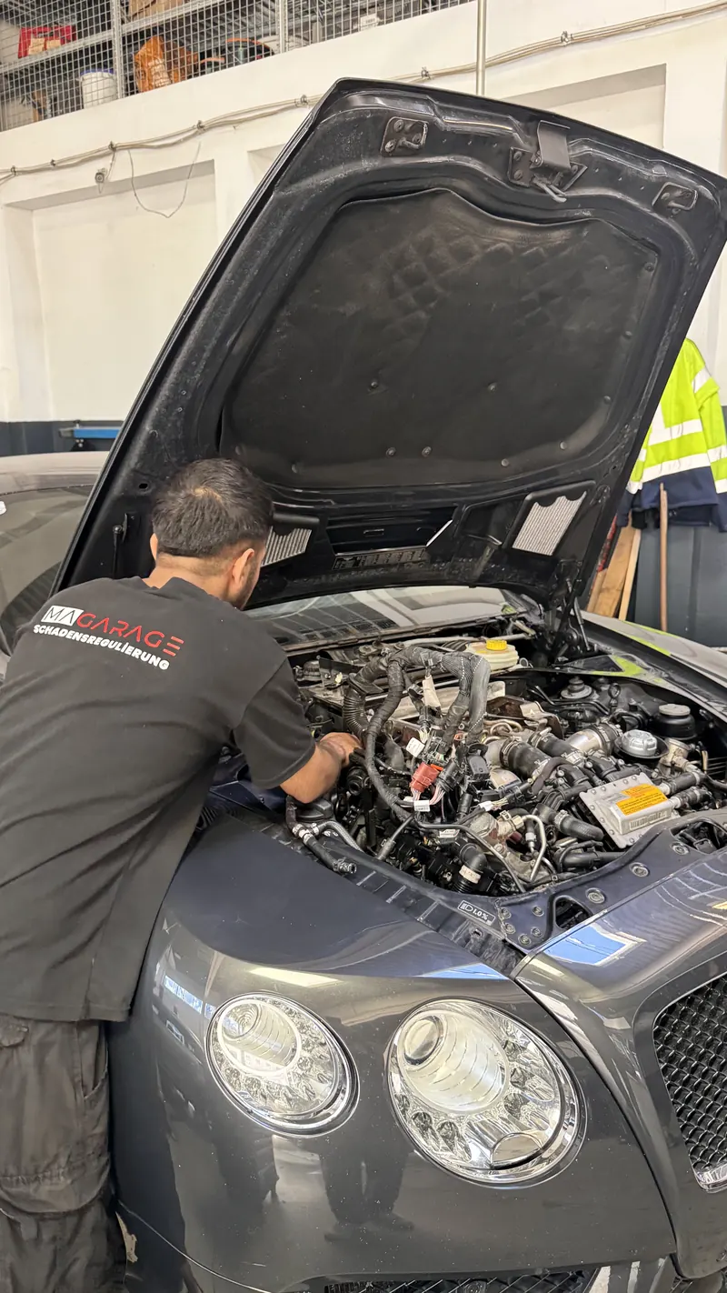 Mechaniker der Magarage arbeitet im Motorraum eines Oberklassefahrzeugs in Wien Liesing