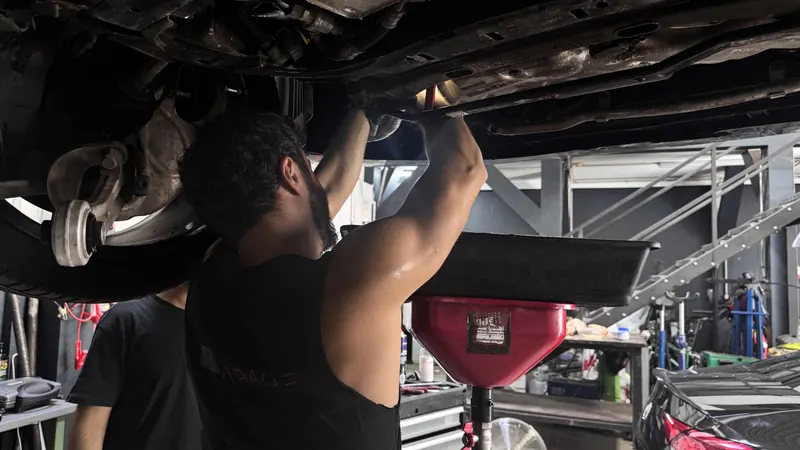 Altöl wird an einem Fahrzeug auf der Hebebühne in der Magarage abgelassen