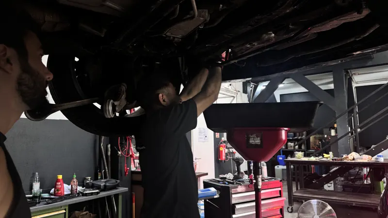 Mechaniker arbeitet unter einem angehobenen Fahrzeug in der Werkstatt der Magarage