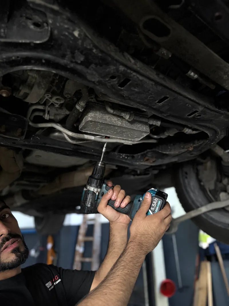 Detailarbeit am Unterboden eines Pkw auf der Hebebühne in Wien Liesing