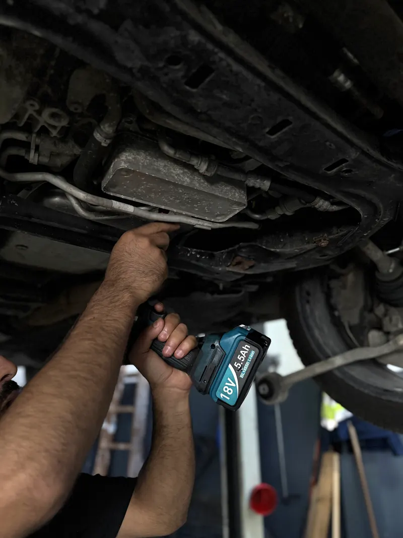 Arbeit mit dem Akkuschrauber am Unterboden in der Kfz-Werkstatt Magarage
