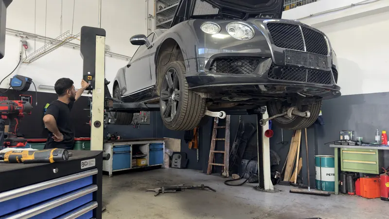 Unterbodenkontrolle an einem angehobenen Fahrzeug in der Kfz-Werkstatt Magarage
