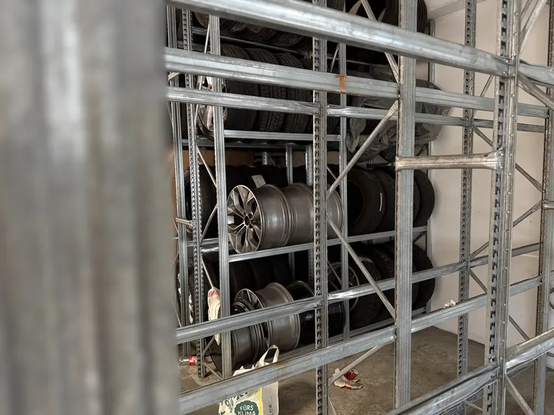 Eingelagerte Kompletträder und Reifen auf den Regalböden im Reifenlager der Magarage