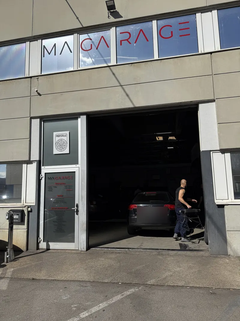 Werkstatthalle der Magarage in Wien Liesing mit geöffnetem Tor und Fahrzeug in der Einfahrt