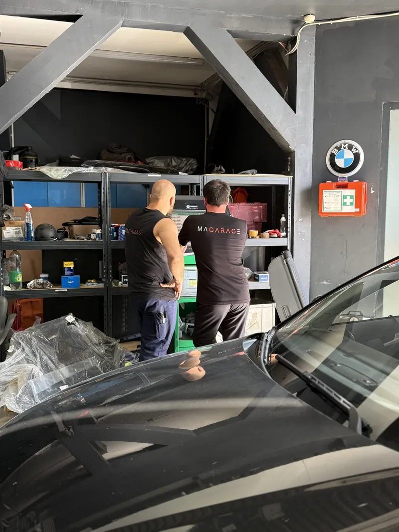 Zwei Mitarbeiter der Magarage am Teileregal in der Werkstatt in Wien Liesing