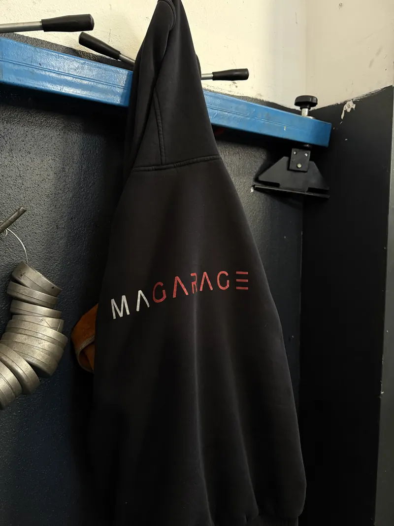 Arbeitsschürze mit Magarage-Logo an der Wand der Werkstatt in Wien Liesing