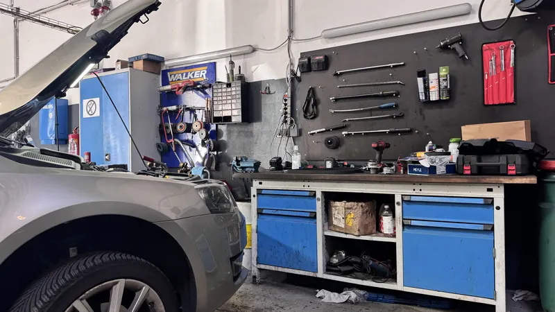 Werkzeugwand und Werkbank in der Kfz-Werkstatt Magarage, davor ein Fahrzeug mit offener Haube